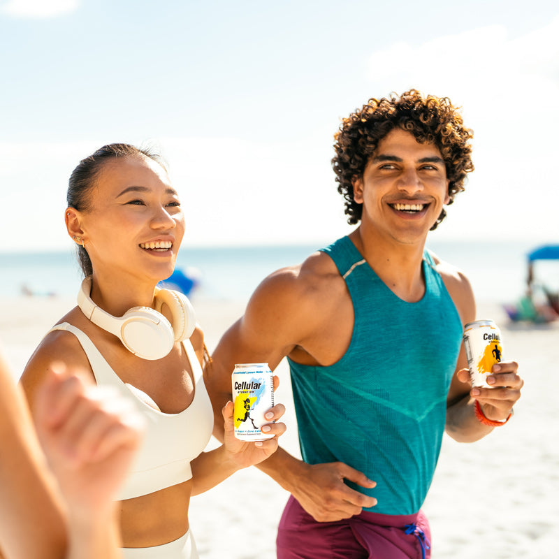 Cellular Hydration Man and Woman Jogging on Beach Holding Cans