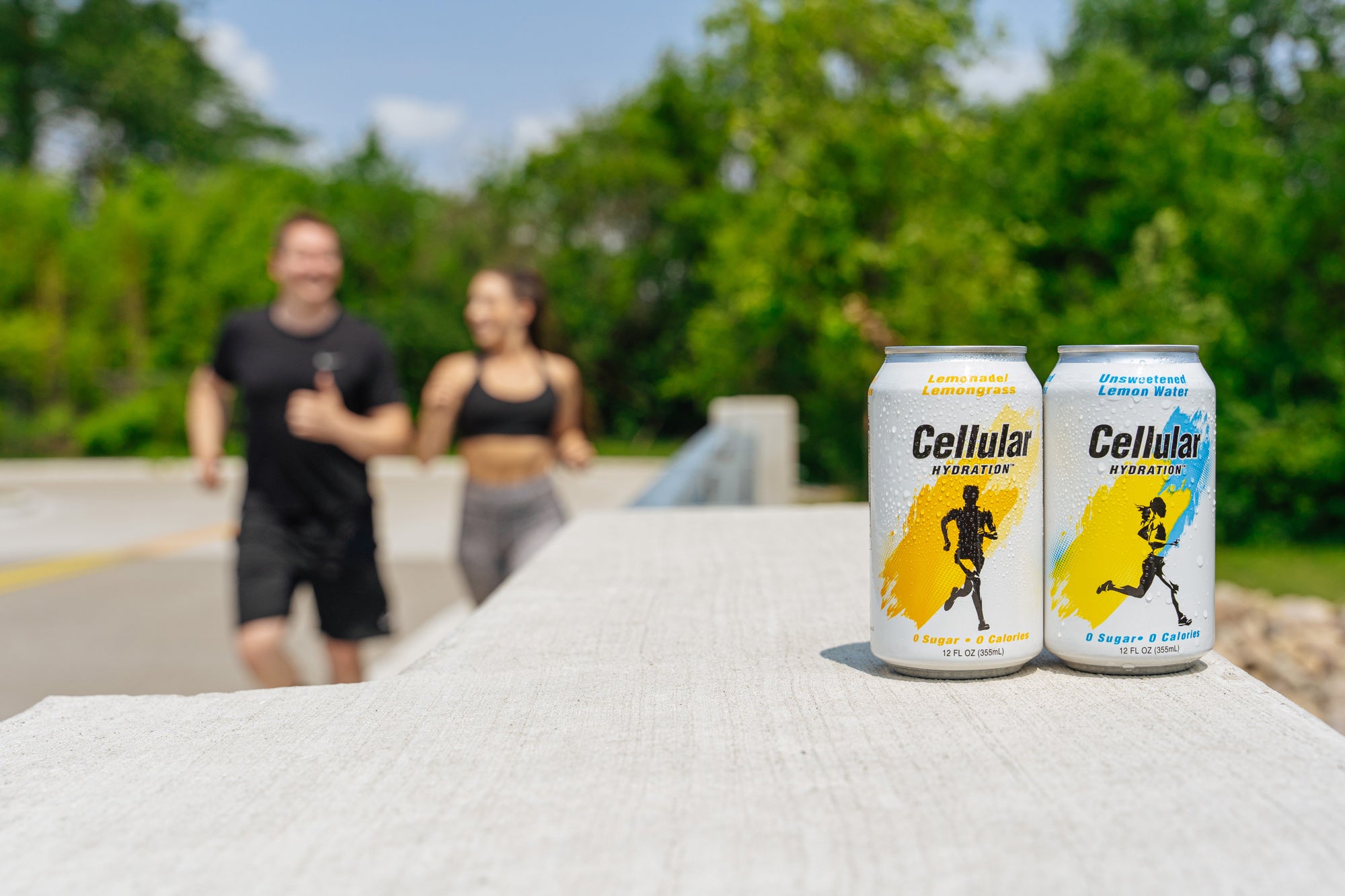 Two cans of Cellular Hydration in the foreground with man and woman jogging in background