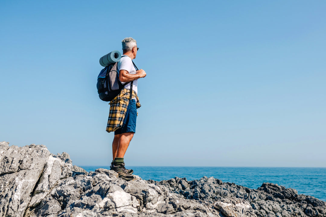 Middle age man hiking along a rocky shoreline